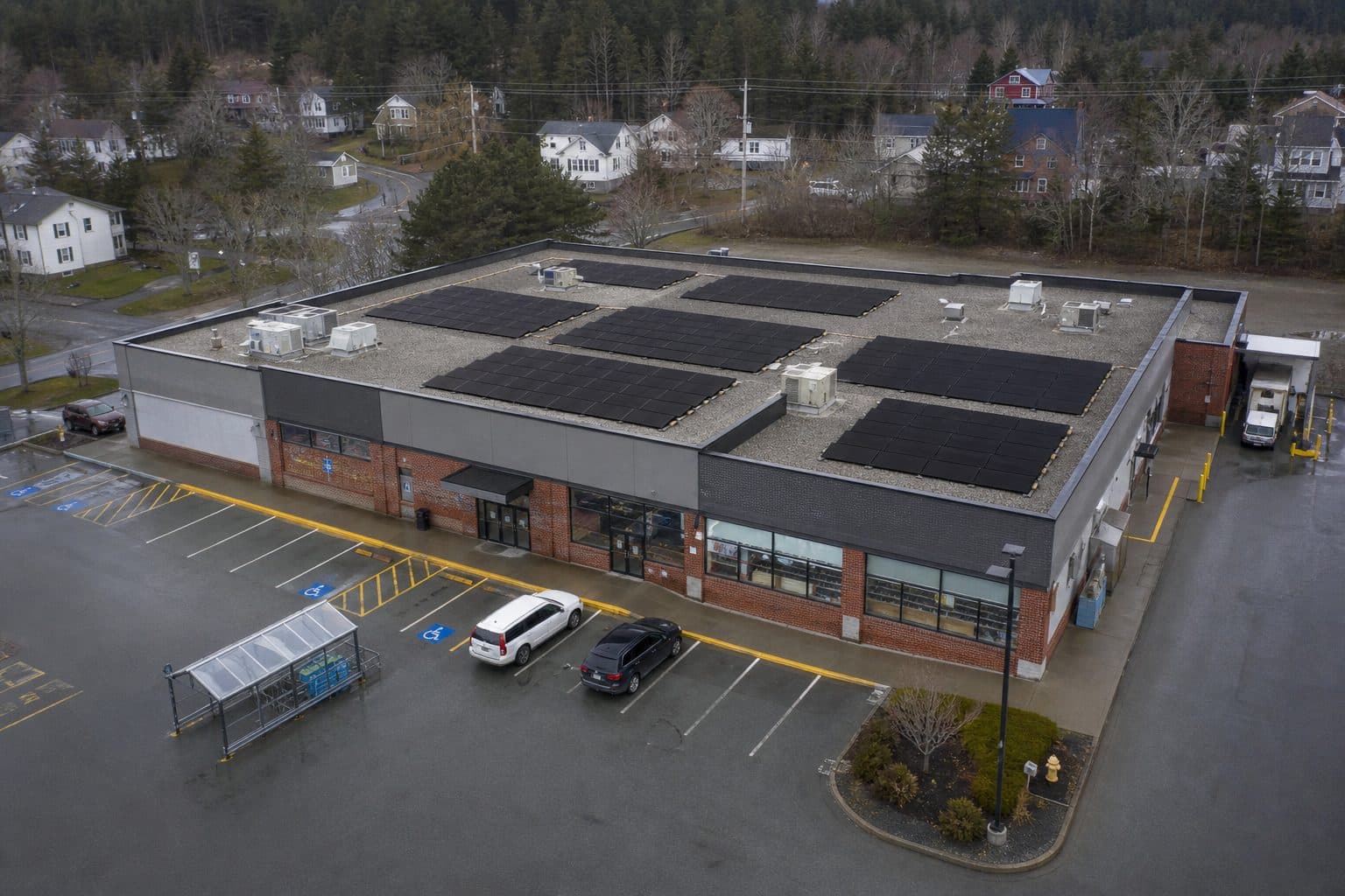 An aerial view of a retail plaza with solar panels across its flat roof