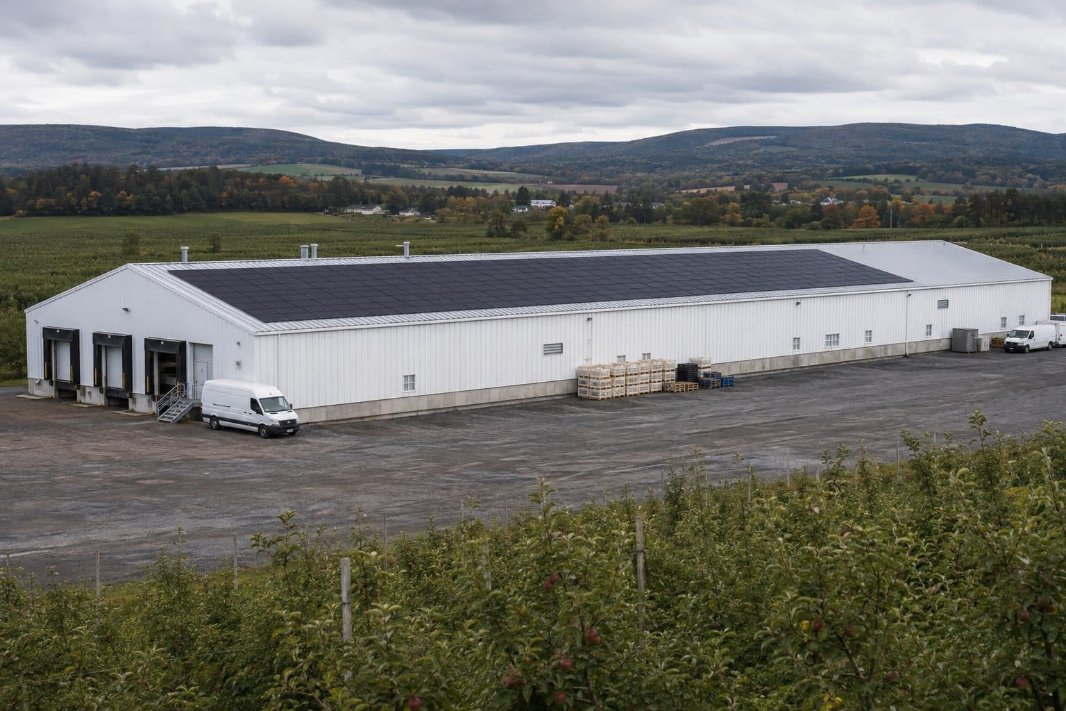 An aerial view of a white warehouse with a full rooftop solar array